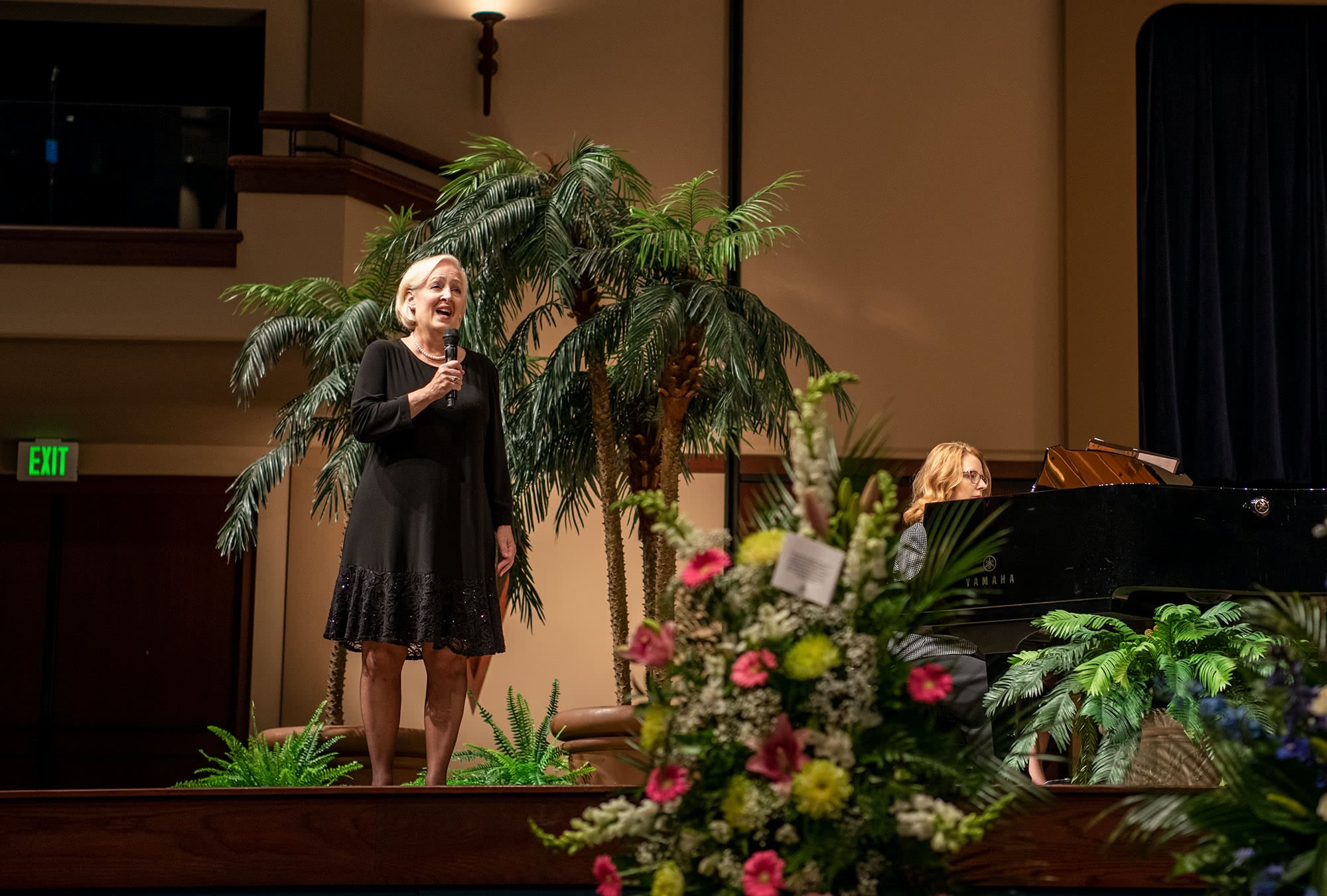 Woman in a black dress singing during the funeral service. 