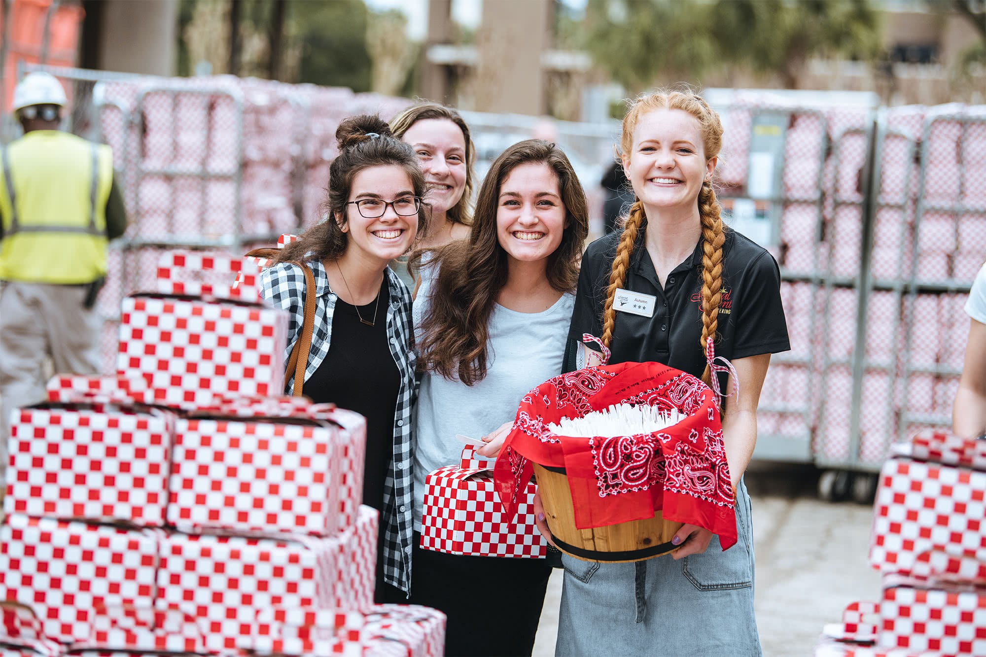 Four female PCC students standing together with picnic boxed lunches. 