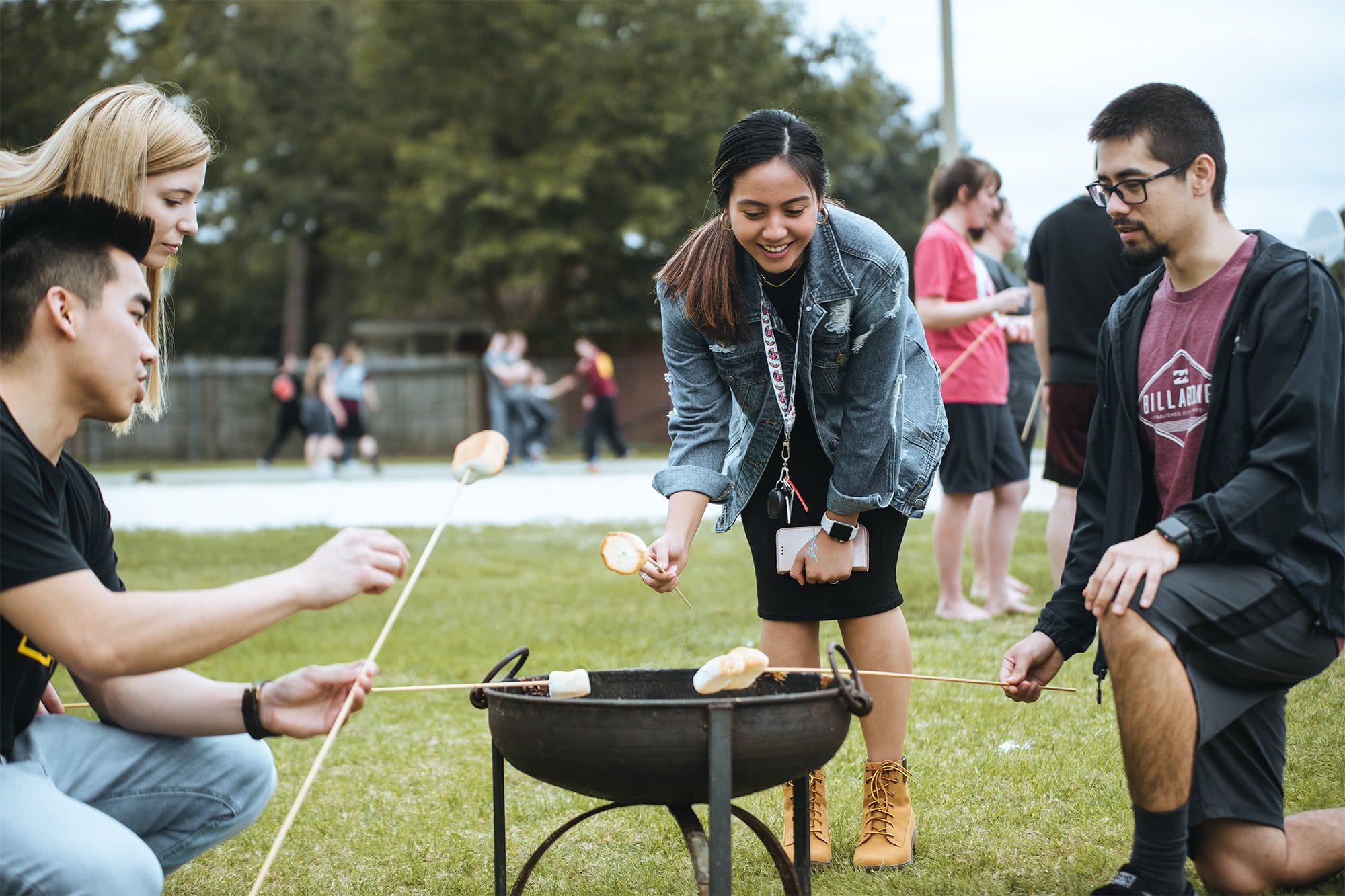 Four PCC students roasting marshmallows together at the 2020 PCC Bible Conference picnic. 