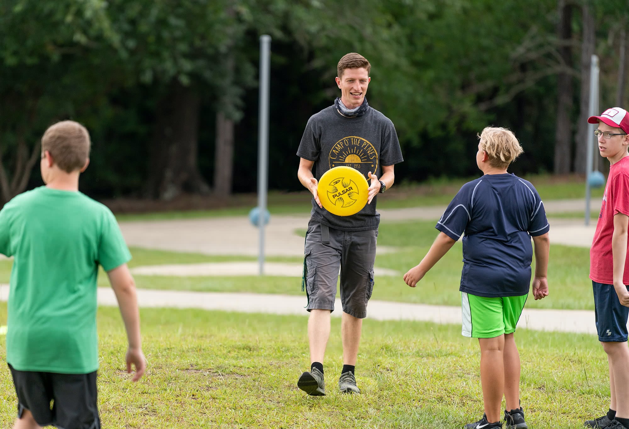 Camp O the Pines counselor playing frisbee with campers. 
