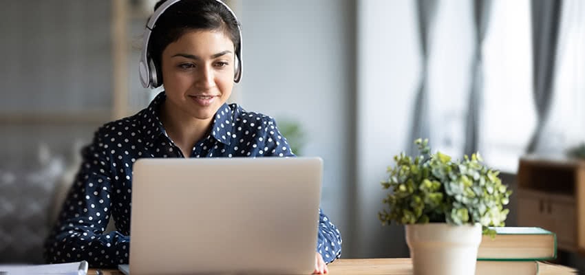 Female student wearing headphones and studying on a laptop.