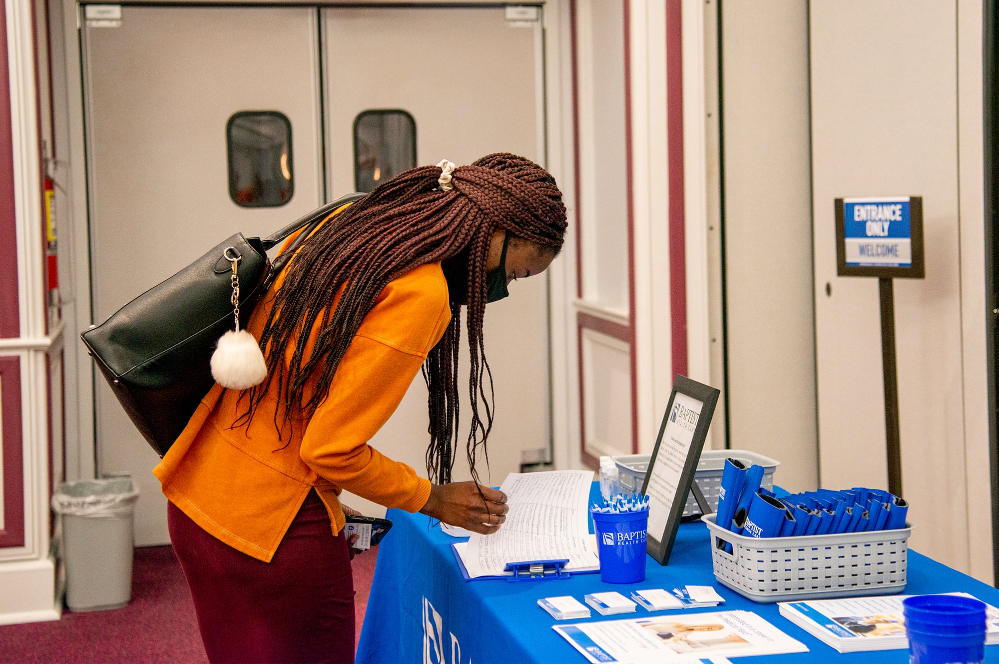 Female student looking down at a form at a booth during the Health Professions Career Fair. 