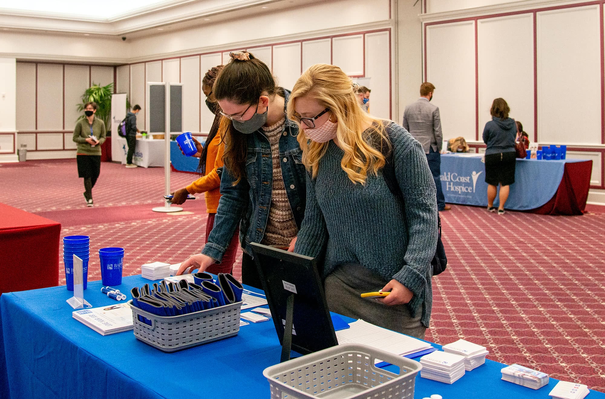 Two female students looking at information at a booth at the Health Professions Career Fair. 