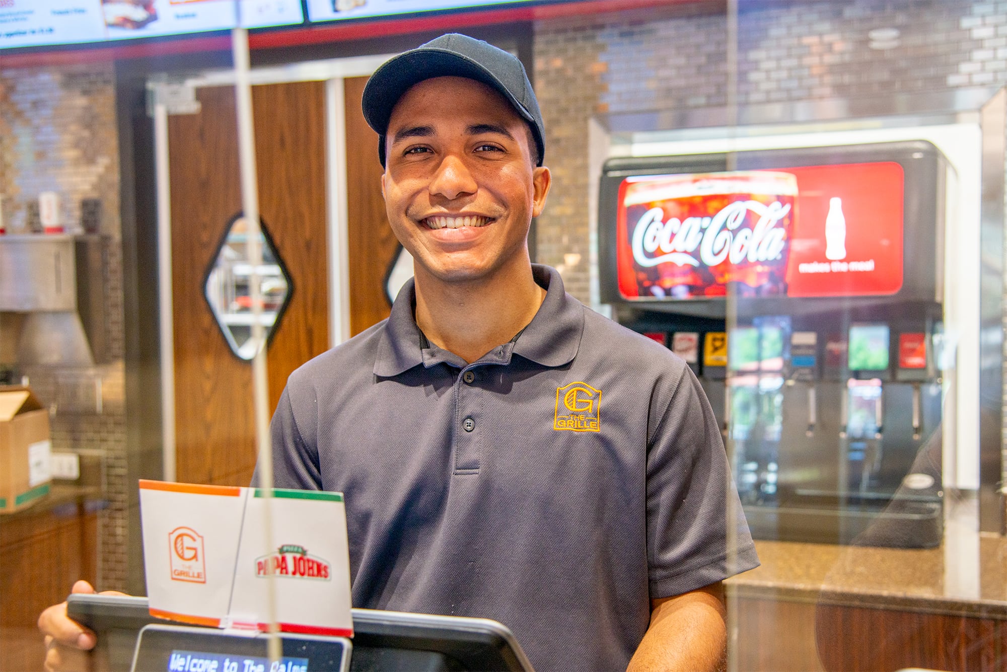 Male student worker at a register working at Palms Grille. 