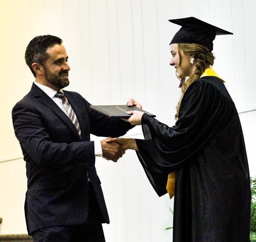 Nathan Reeves shaking hands with a graduate. 