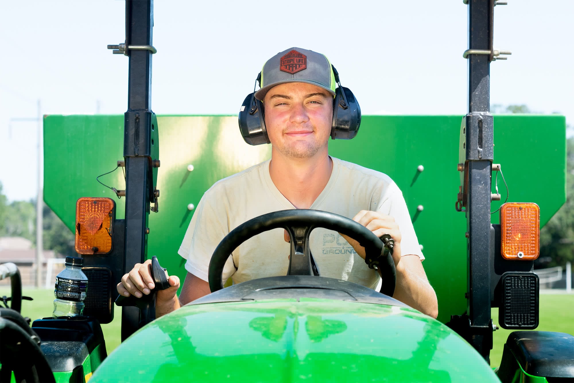 Male student grounds worker driving a tractor.  