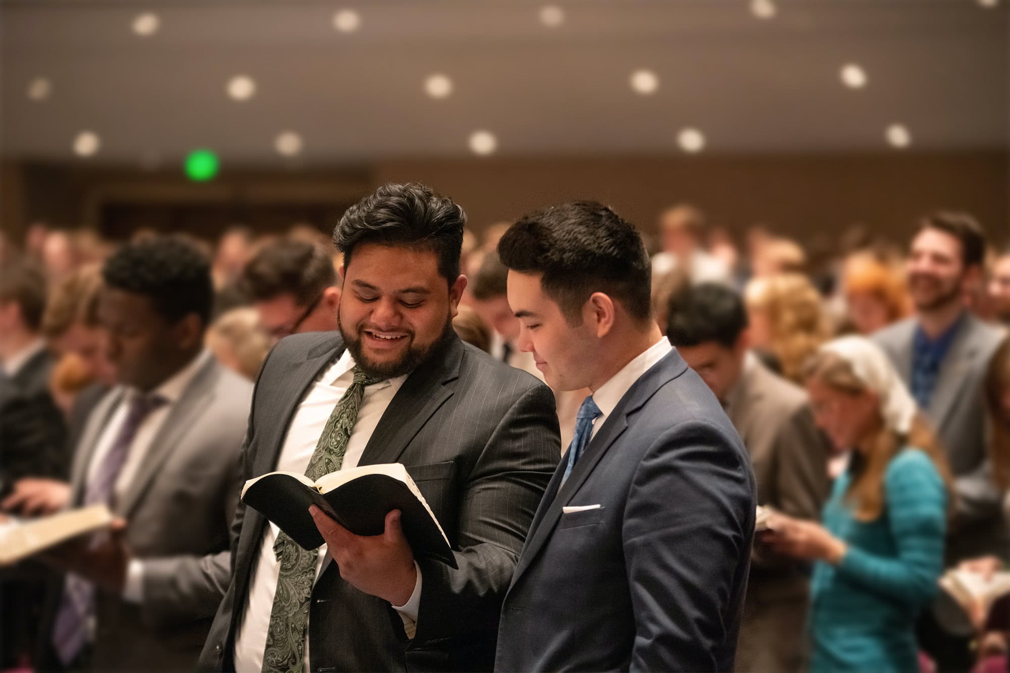 Two guys standing during congregational Scripture reading at Bible Conference