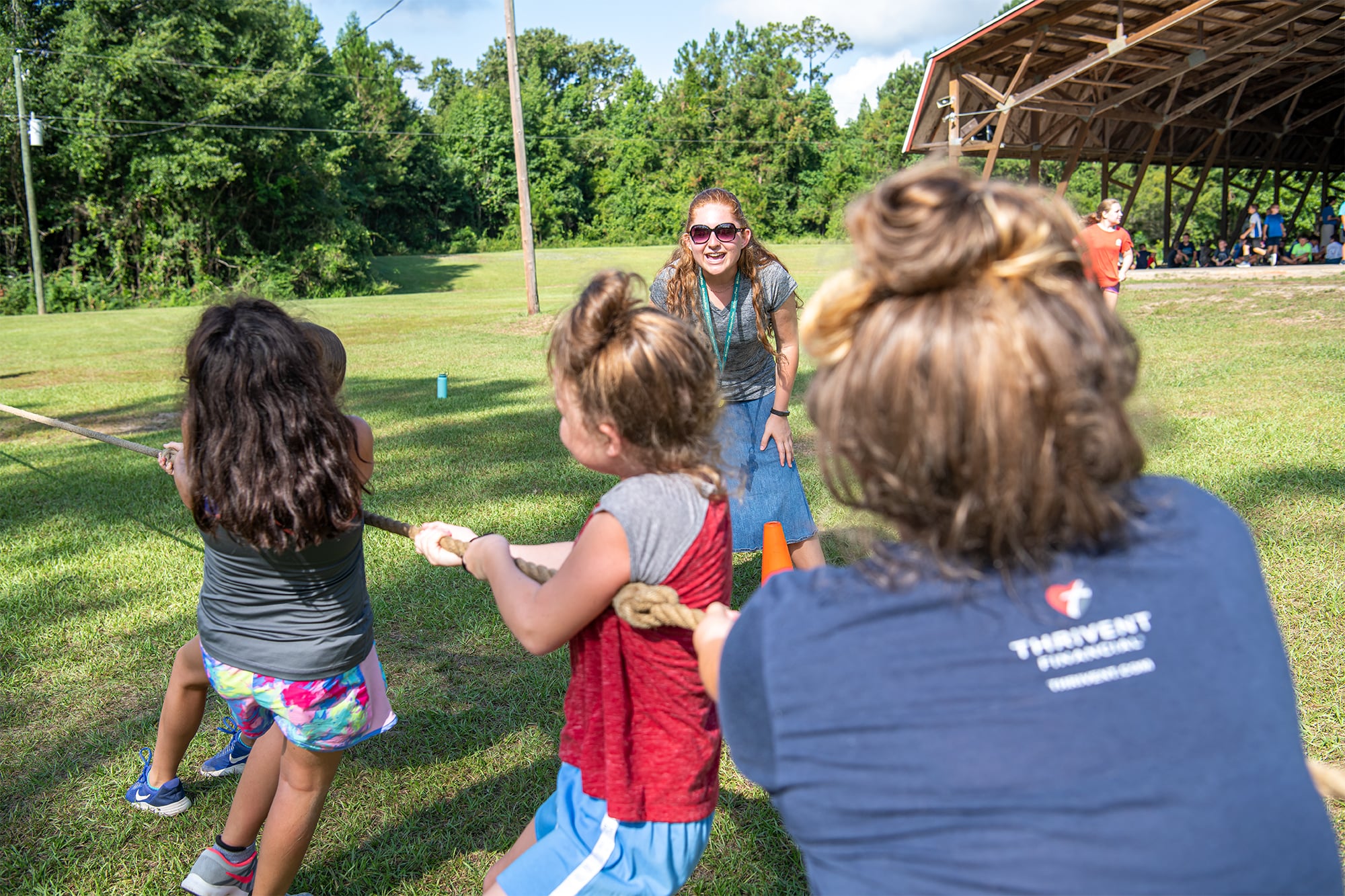 Camp o' the Pines camp counselor encouraging girls during tug of war game. 