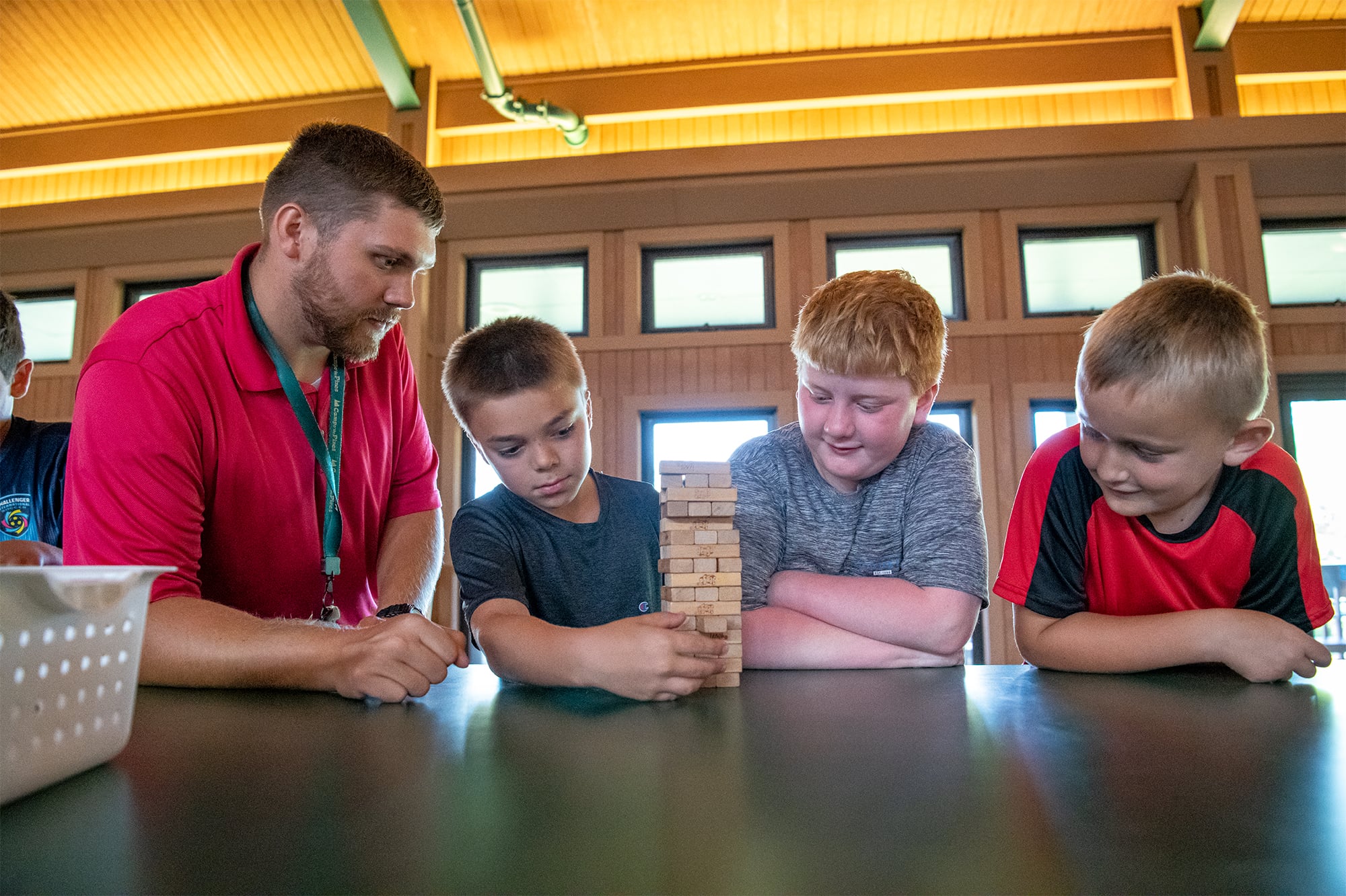 Camp o' the Pines counselor playing Jenga with boys at camp. 