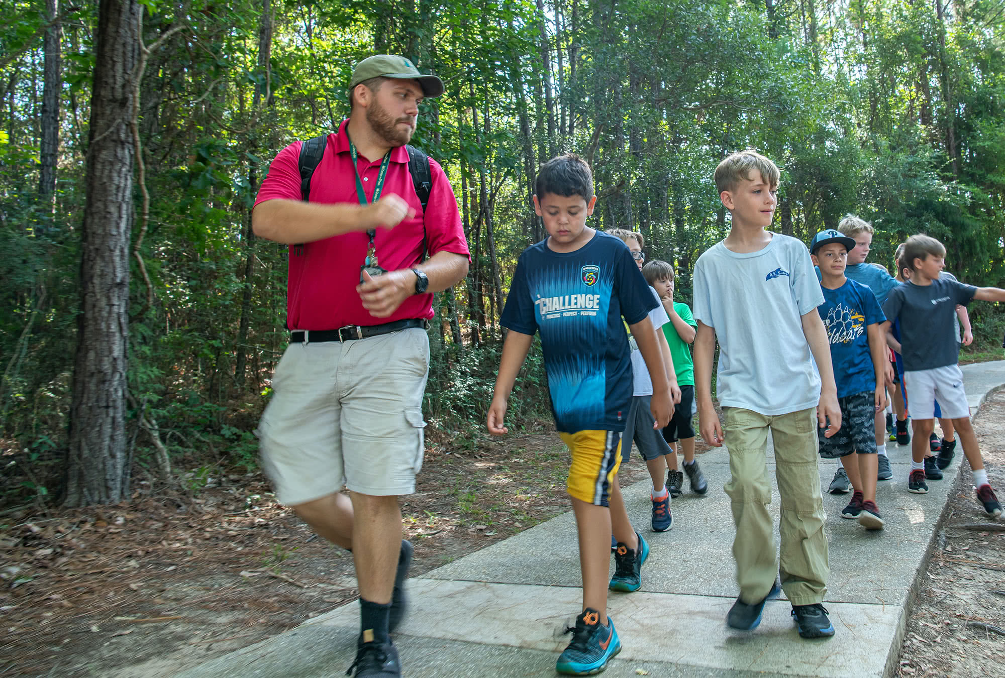 Male Camp o' the Pines counselor walking with a group of boys at camp. 