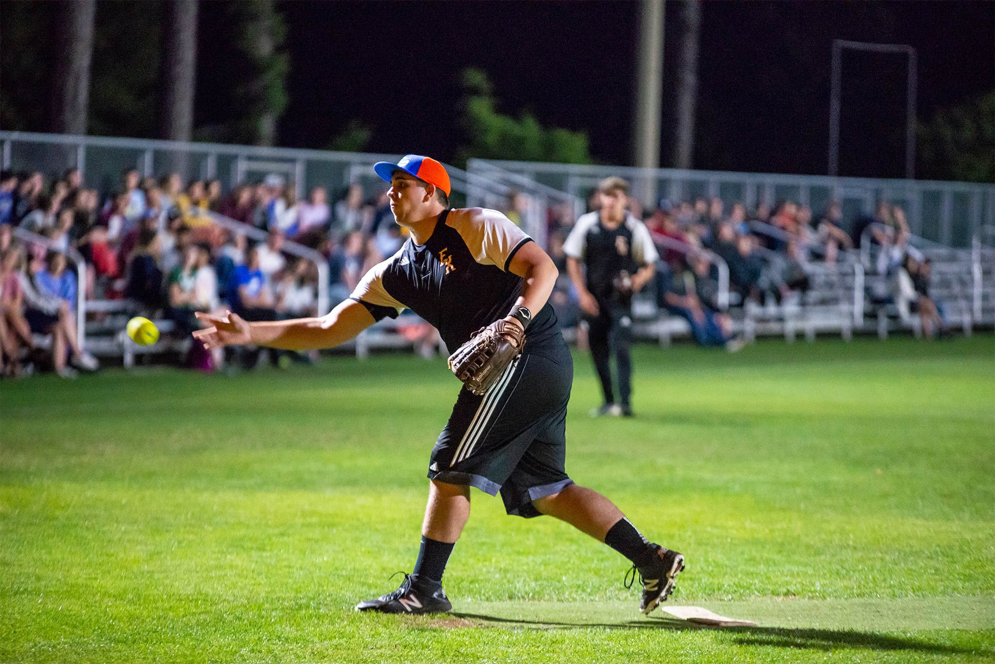 Men's collegian softball player pitching the ball. 
