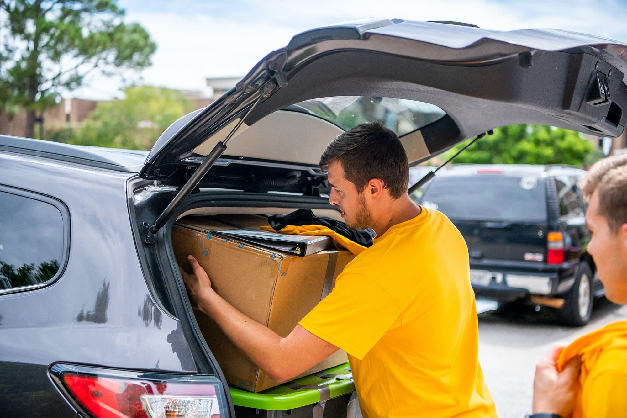 A male greeter helps a student unpack his car