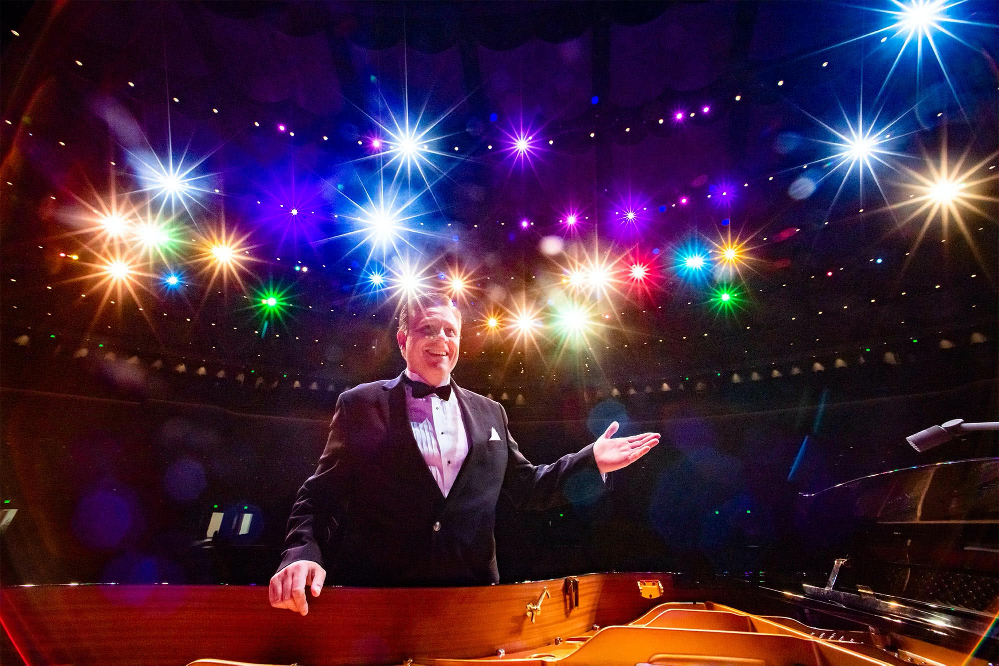 Anthony Kearns faces the stage with multi-colored lights shining behind him
