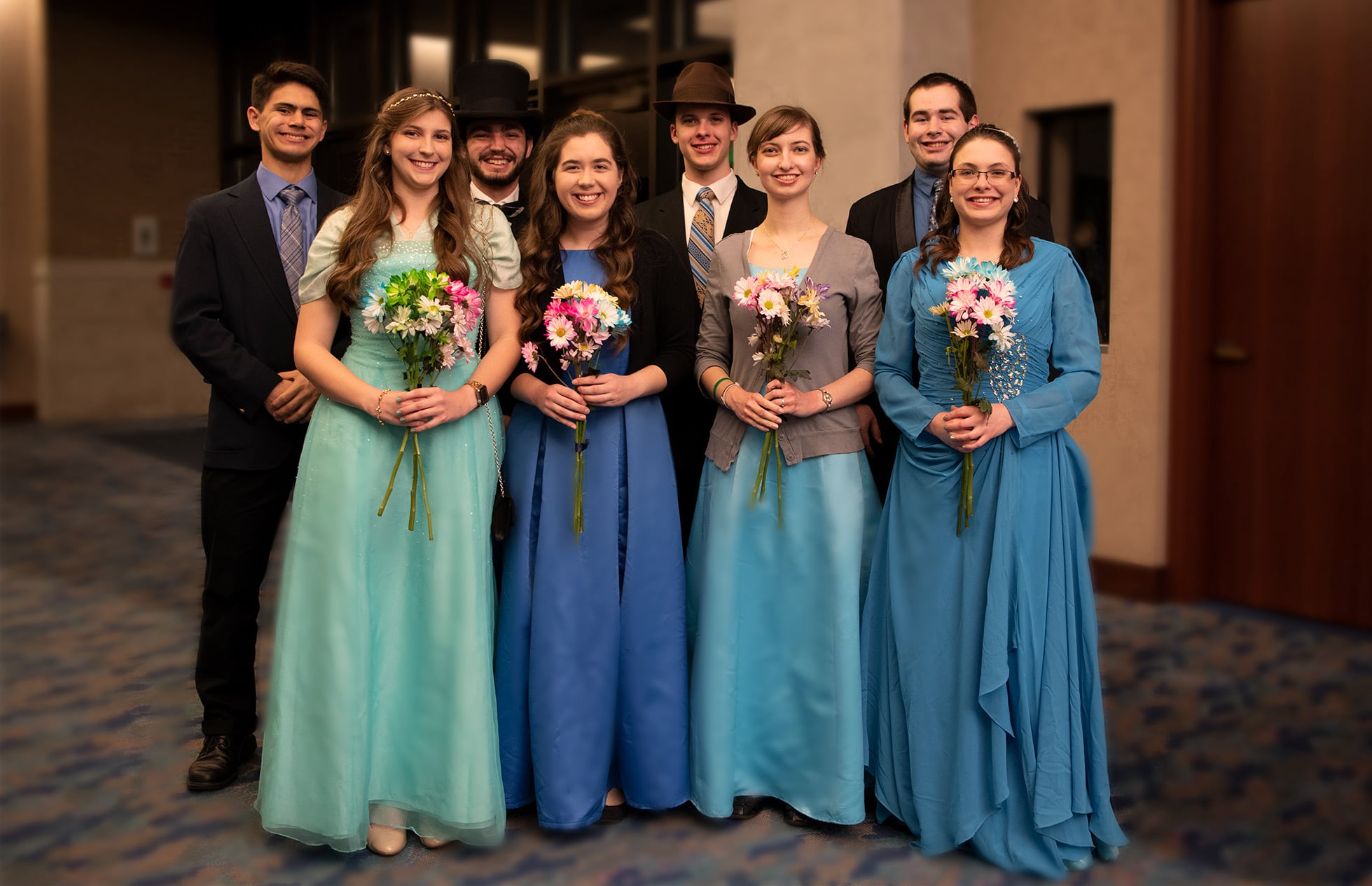 A group of four girls in blue dresses pose for a picture with four guys