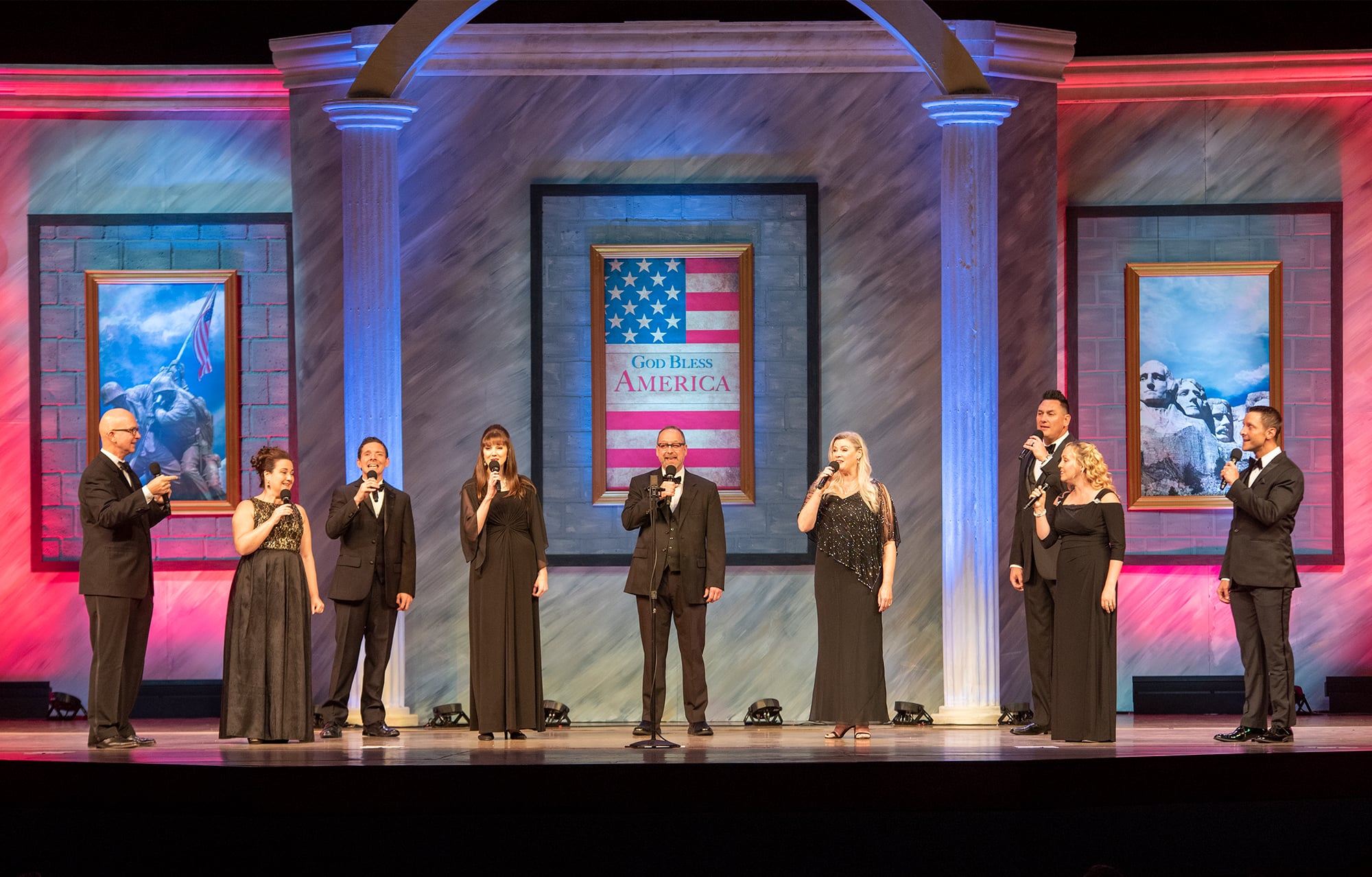Liberty Voices wearing black suits and dresses and singing on the PCC Crowne Centre stage. 