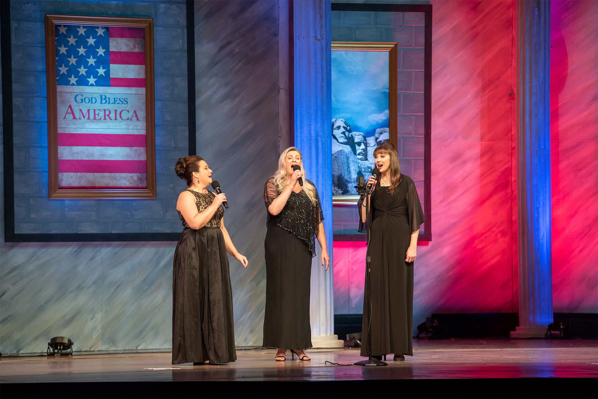 Female Liberty Voices singers wearing black dresses and singing together.