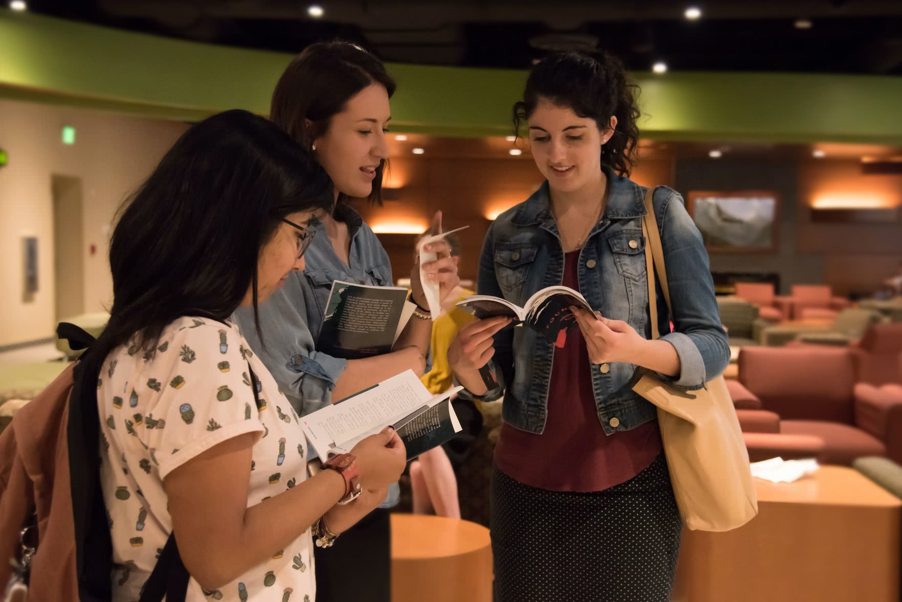 Three female students looking at copies of 2019 Fountains. 