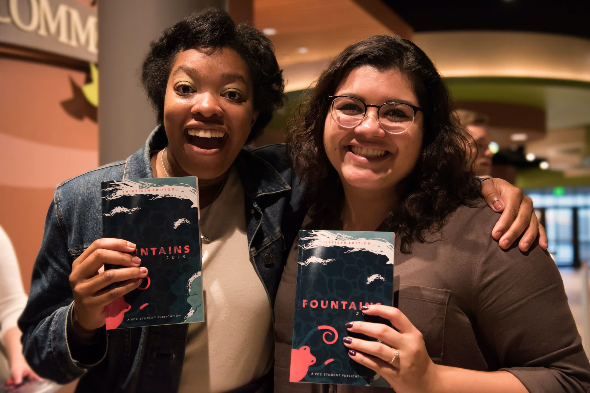Two female students smiling and holding copies of 2019 Fountains. 
