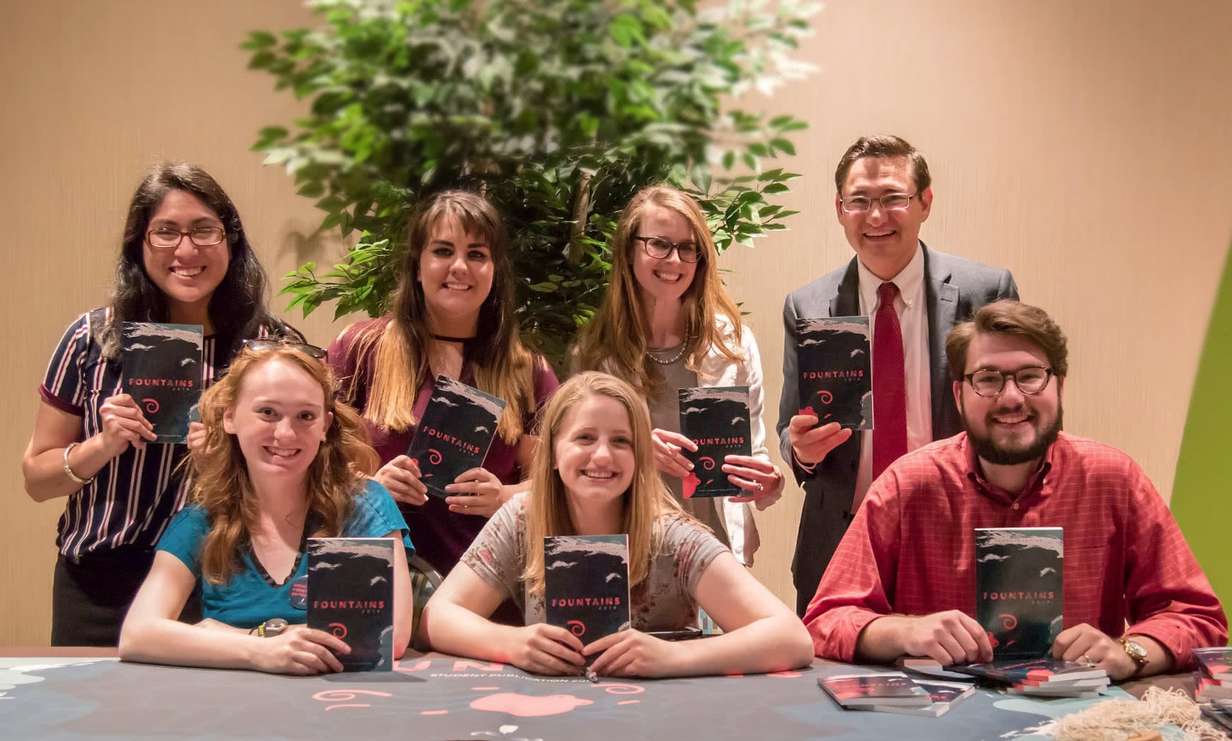 A group of people holding up copies of Fountains 2019. 