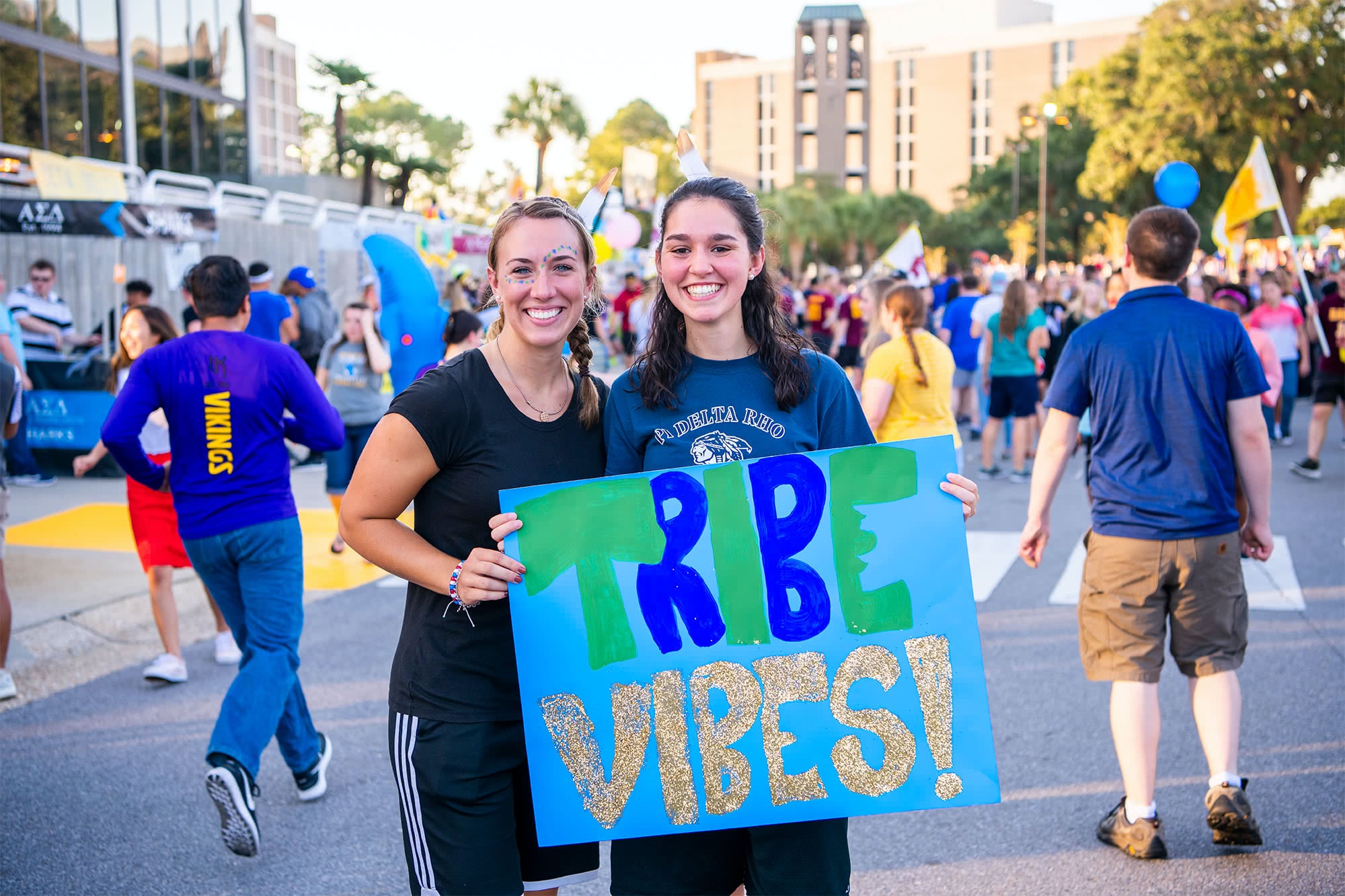 Two members of the Aztec collegian hold a sign that says "tribe vibes"