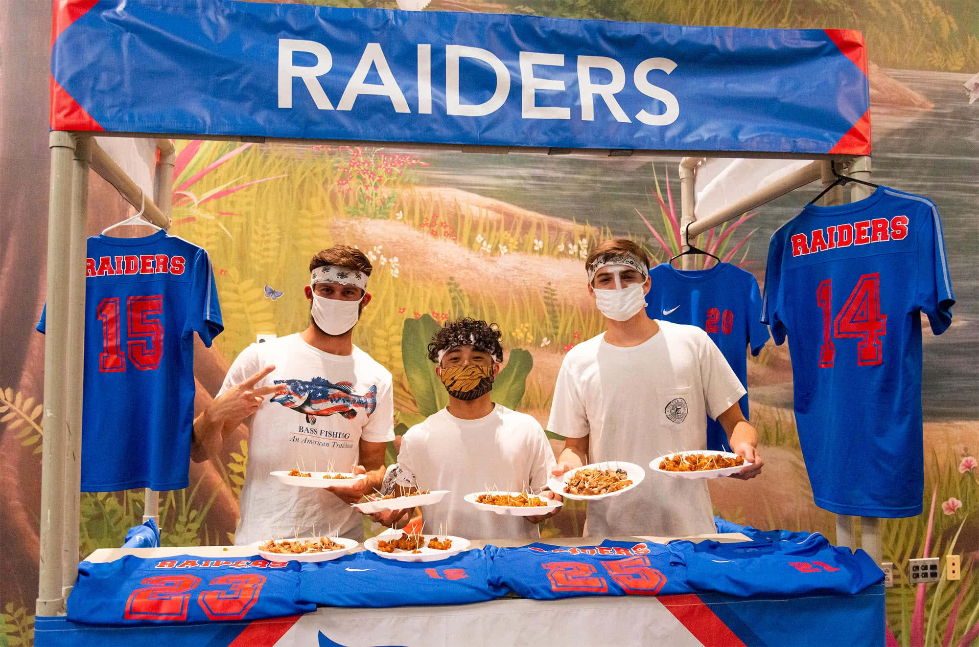 Three guys pose at the raiders' booth