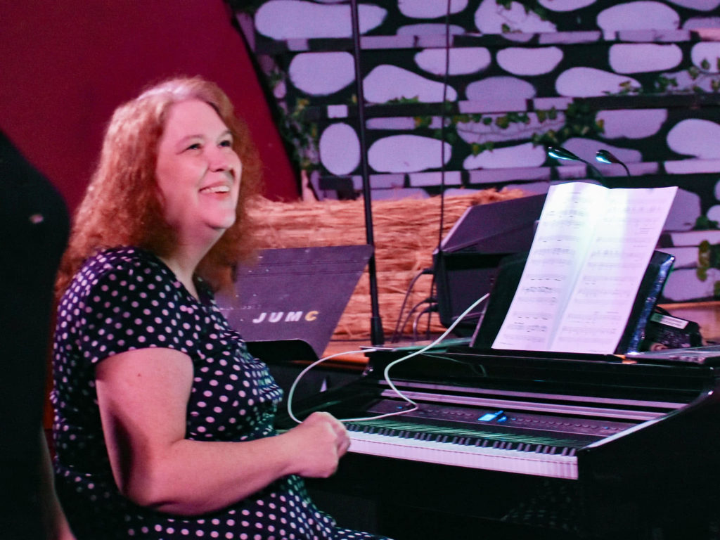 Melissa Lingle sitting at a piano and smiling. 