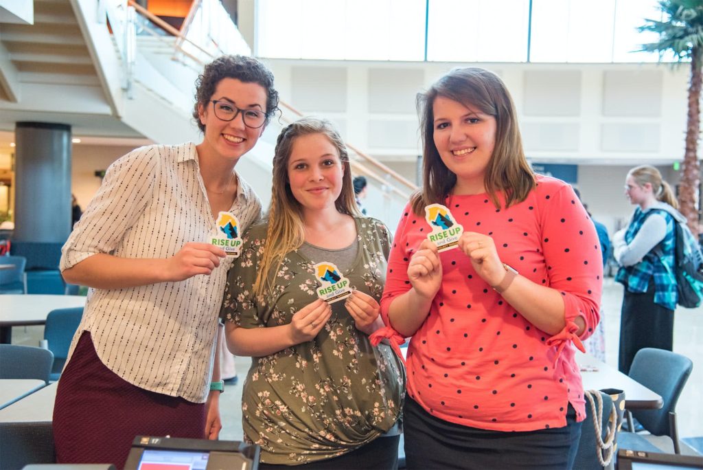 Three friends pose for a picture with the project stickers in the Commons