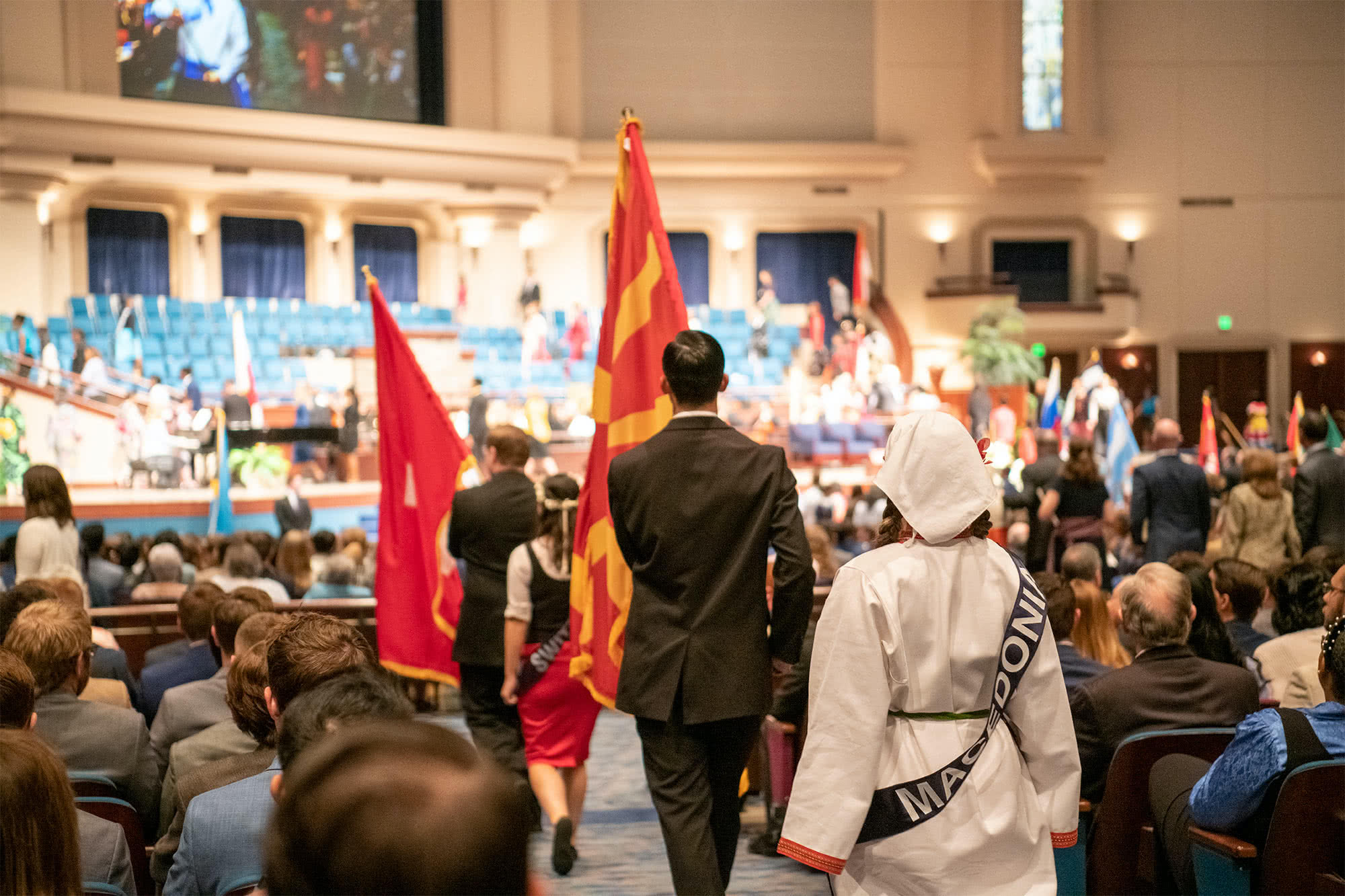 Male PCC students walking with their countries' flags during the Parade of Nations. 