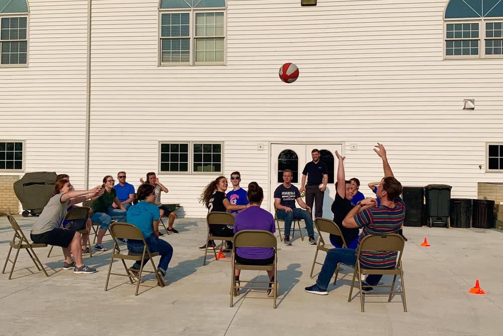 People sitting in chairs and playing a game with a ball. 