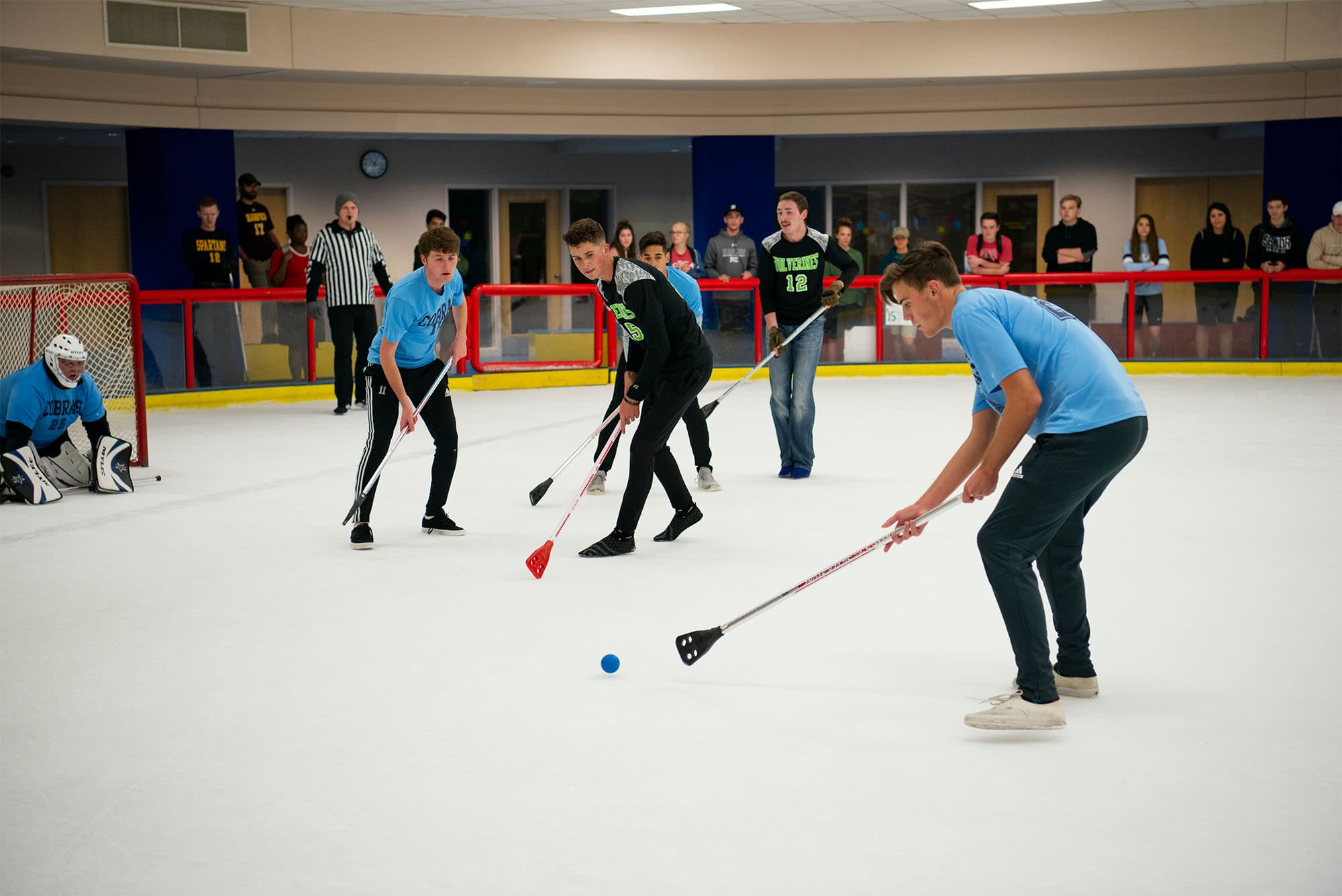 Men's collegian Wolverines and Cobras playing broom hockey. 