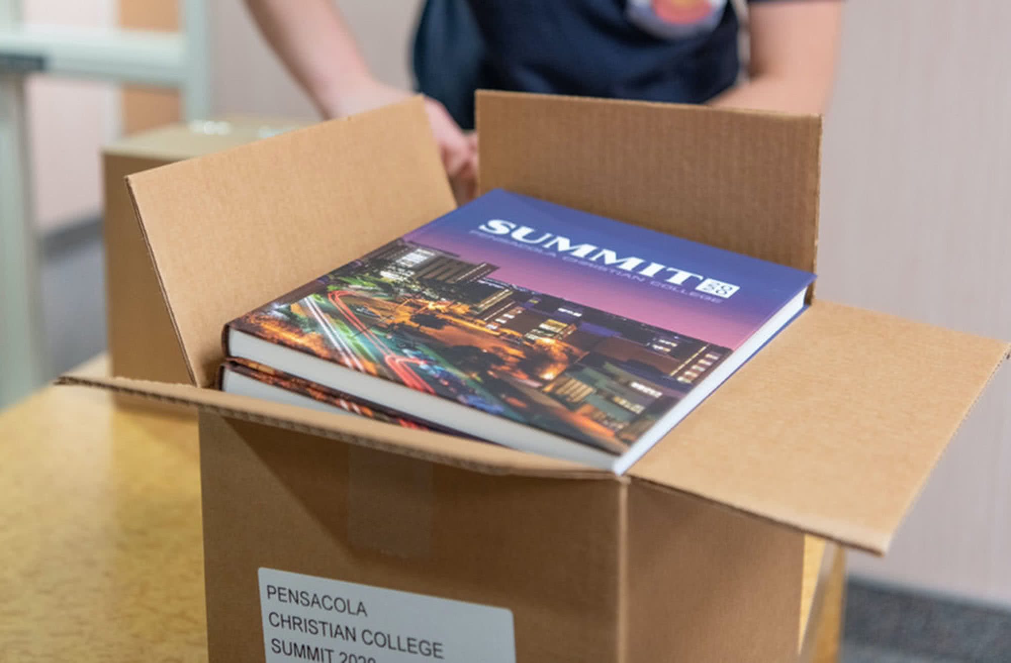 Summit Yearbooks stacked in a cardboard box.
