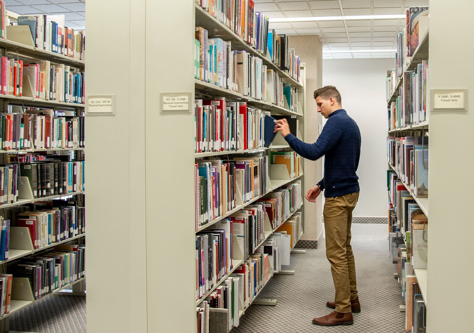 A male student picks out a book in the library