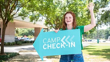 Teen Extreme camp counselor holding a camp check-in sign.