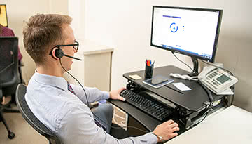 Enrollment advisor wearing a headset and working on a computer.