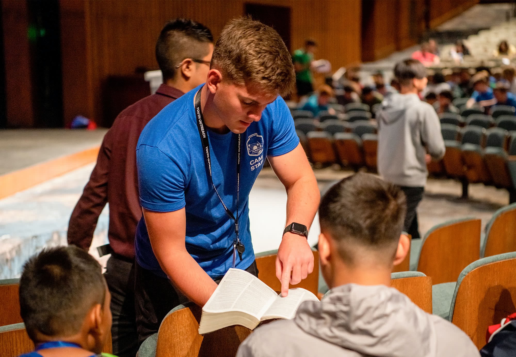 A male Teen Extreme counselor showing a camper something in the Bible. 
