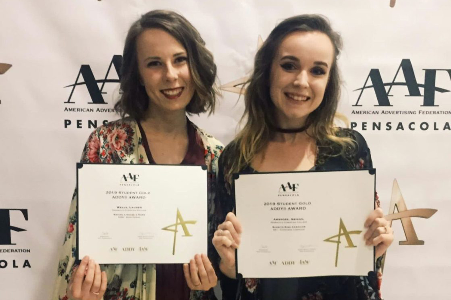 Two female students pose with their certificates