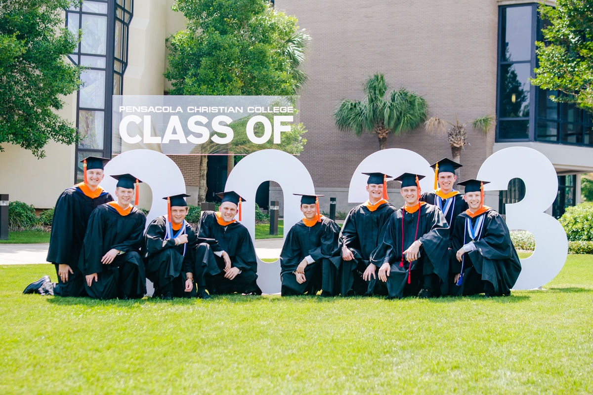 Arts and Sciences graduate guys pose in front of 2023 sign during their Commencement event.